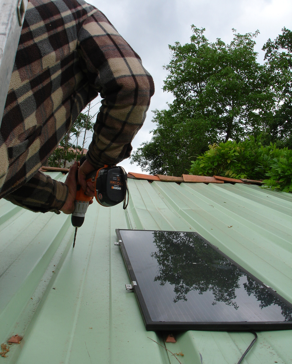 [Fabrice+drilling+holes+in+the+roof+to+fit+the+panels.JPG]
