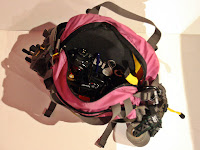 a pink backpack with a few objects inside