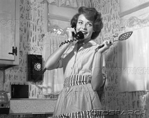 [1950s-1960s-smiling-woman-talking-wall-telephone-holding-spoon-~-t611.jpg]
