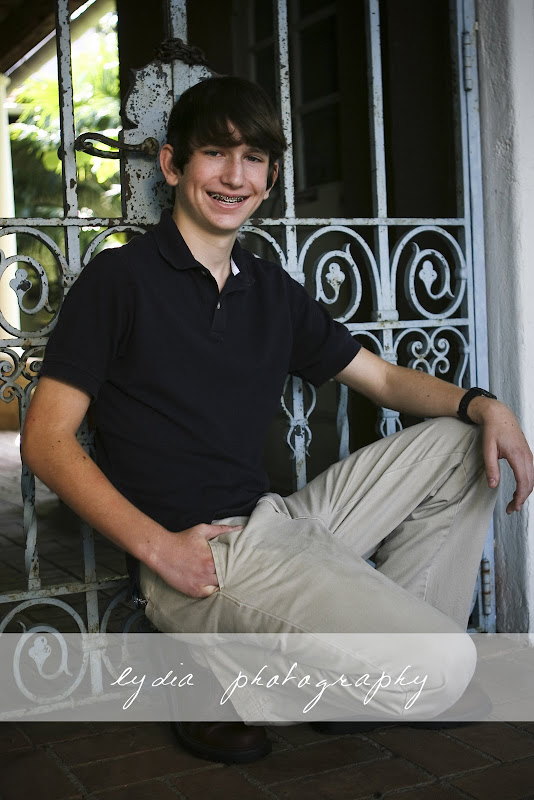 Senior sitting infront of a gate at lifestyle senior portraits at the Dallas Arboretum in Texas