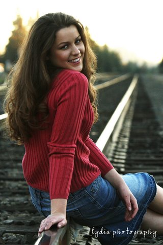 Senior sitting on the railroad tracks with back to camera at lifestyle senior portraits in Colfax, California