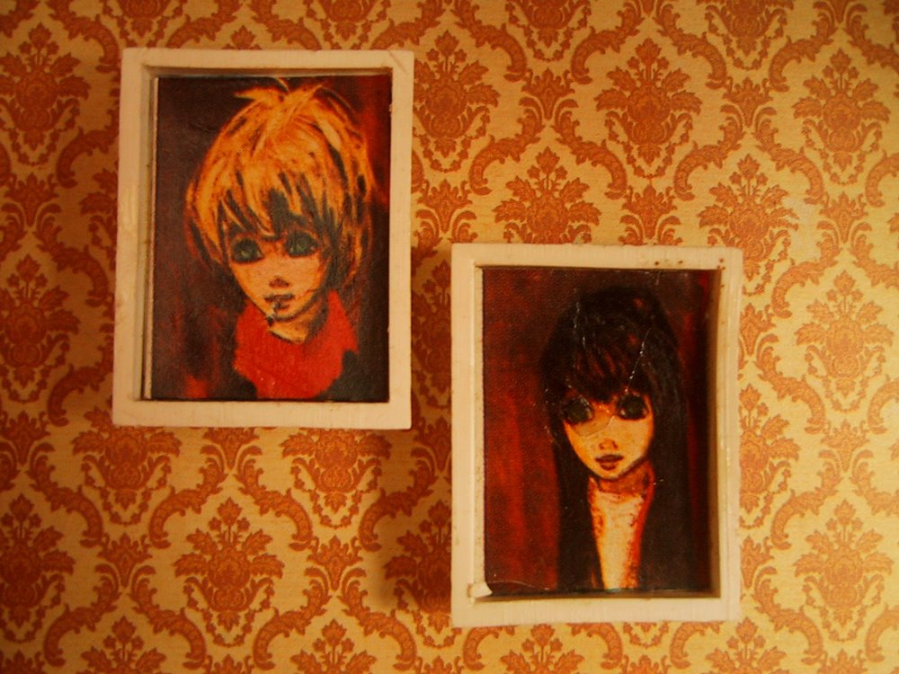 Two vintage doll's house big eye' pictures on a lounge wall.