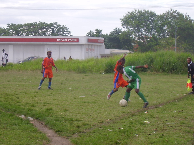 SANTOS STRIKER LESLIE CONTESTING THE BALL AGAINST A DMP PLAYER WHILST BEING WATCHED BY JASON