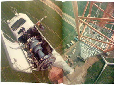 Construction worker sitting atop a 300-foot tall wind turbine, shot from above