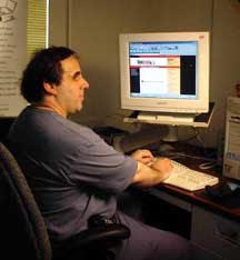Peter Scialli at a computer, half turned to the camera, Bookshare.org on the screen