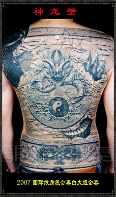 A full back dragon tattoo resembling a wall sculpture.